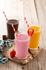 Chocolate, strawberry and vanilla milkshakes on rustic wooden table