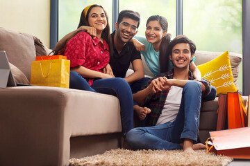 A Group of youngsters smiling together in living room after a shopping spree.	