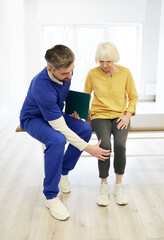 Physiotherapist examining patient's knee. Senior patient with knee injury visit her physiotherapist