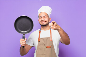 young hispanic man pointing or showing. chef concept
