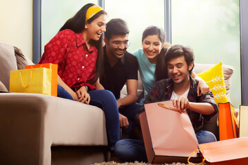 A Young man showing his purchase to his friends in a living room.	