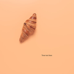 Fresh croissant on a pastel peach background. Creative layout. Top view, flat lay.