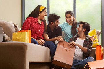 A Group of youngsters talking happily in living room after a shopping spree.	