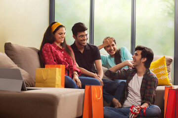 A Group of youngsters talking happily in a room after a shopping spree.	