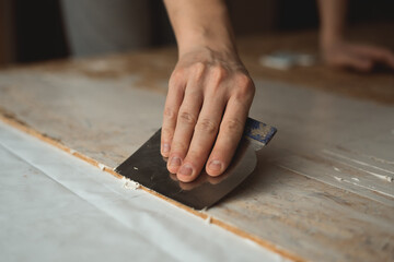 Hand applies the putty with a spatula