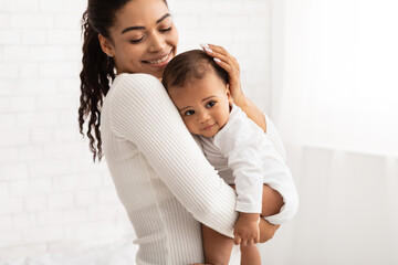 Happy African Mom Holding Baby Toddler Standing Indoors