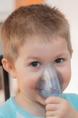 Little boy using nebulizer during inhaling therapy. Little boy making inhalation with nebulizer at home. Close up portrait of boy taking inhalation for asthma prevention.