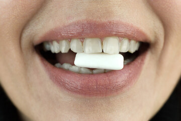 Chewing gum in a woman teeth close-up.