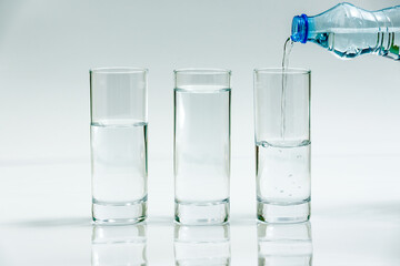 Water bottle pour water Water into three glasses - different level, on white background - three glasses of water