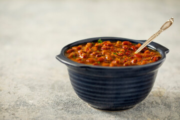 A BOWL OF RAJMA CURRY WITH SPOON KEPT ON FLOOR	