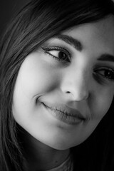 Close up black and white portrait of a beautiful young smiling woman with long dark hair