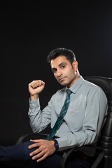 PORTRAIT OF AN ADULT MAN IN FORMALS SITTING AND LOOKING AT CAMERA	