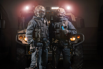 Two men in military uniforms stand in a hangar with a truck in the background. SWAT concept.
