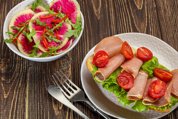 Smoked sausage and cream cheese sandwiches on a plate. Decorated with dill herbs. On a dark wooden background.