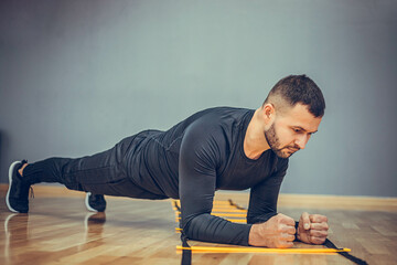 Fitness training athletic sporty man doing plank exercise in gym or home concept. Bearded man exercising workout aerobic at grey background.