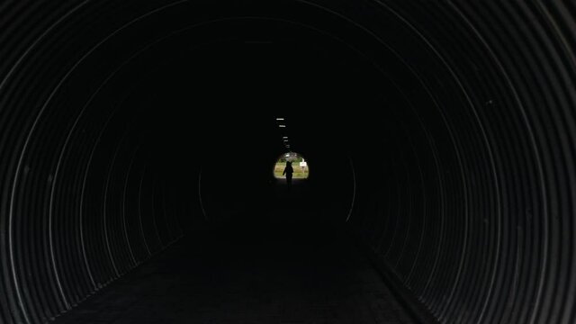 Shooting from a quadrocopter of a young girl running in a dark tunnel. The concept of search for exit a way out of a difficult situation