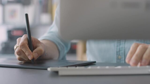 Close up of hands of male architect working on desktop computer in office using graphics tablet- shot in slow motion