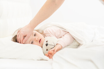Mom checking the temperature of a girl with down syndrome. Ordinary childcare in a family for...