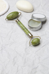  Natural organic skin care product. Home spa and self care concept. Facial serum, jade roller and soap bar with copy space.