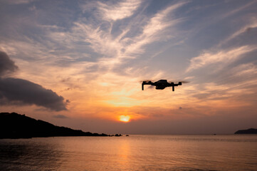 Fototapeta na wymiar Drone flying in the sky at sunset soaring the sea waters.