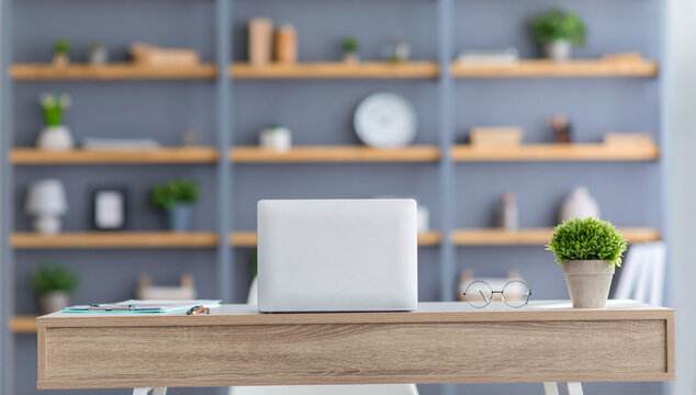 Scandinavian style. Modern design, table with laptop, shelves with books, accessories and potted plants in gray wall