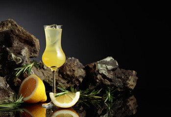 Traditional homemade lemon liqueur limoncello on the black background.