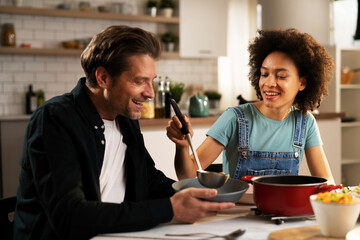 Loving couple eating lunch together at home. Husband and wife enjoying in tasty meal.