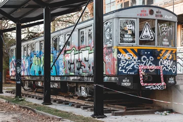 Foto auf Acrylglas Piece of metro train sitting in the outside of the university with graffiti © wazaa08