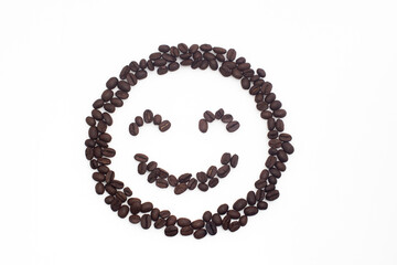 Roasted coffee beans arranged in a smiling face on a white background.