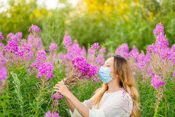 A girl in a medical mask sniffs a bouquet of purple flowers in her hands. Spring aggravation of allergies concept. Security measures during the coronavirus pandemic