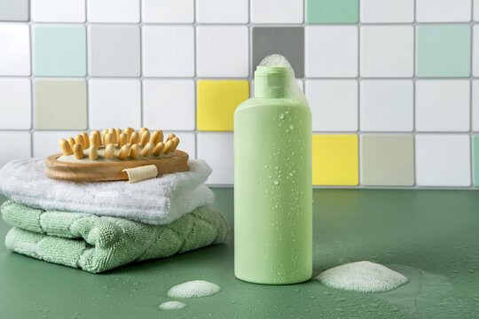 Cosmetic products for hair or skin care standing in the bathroom. Shampoo or shower gel in a light green bottle. Space for text.