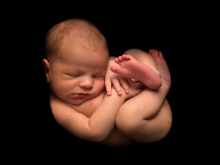 Newborn baby in foetus pose - 424009033