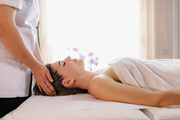 Obraz na płótnie Canvas Spa head massage. Side view brunette woman enjoying relaxing face massage in beauty spa salon