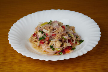 Delicious Peruvian hake and tune ceviche with vegetables, spices and lime on a white plate