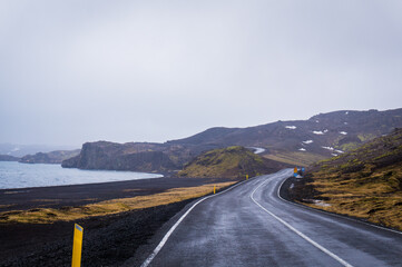 Dark empty Iceland asphalt road with mountain and black beach of Lake Kleifarvatn view near Krysuvik, Reykjanes Peninsula