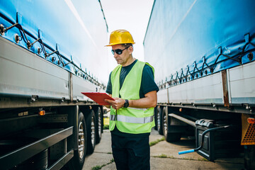 Professional male industrial truck driver with yellow protective helmet performs technical...