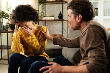 Frustrated young couple arguing at home. Stressed unhappy wife and husband sitting on cauch at home.