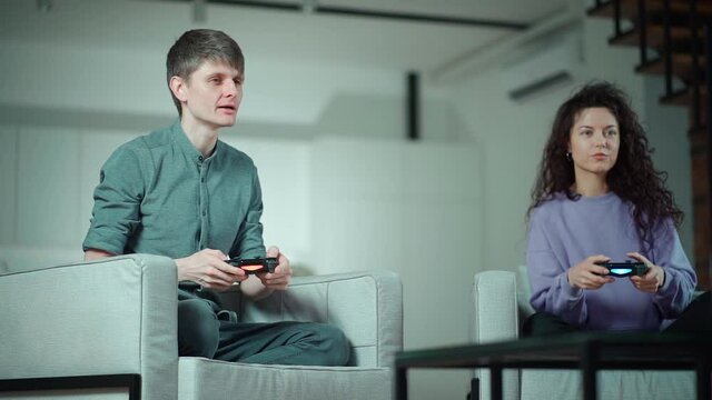 happy couple playing video game with controller on play station at home