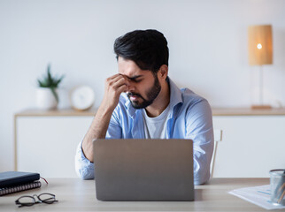 Desperate Eastern Freelancer Sitting At Desk With Laptop, Suffering Lack Of Inspiration
