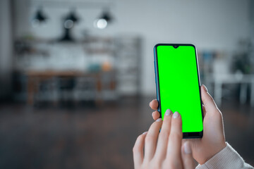 closeup of female hand using or clicking smartphone with green screen at home