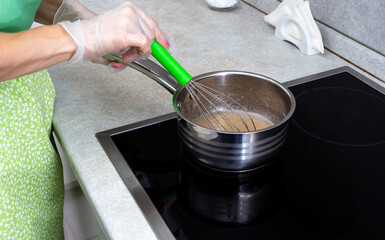 In a saucepan, stir the boiling sugar syrup with a whisk. The cooking process. Selective focus.