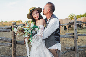 Wedding couple in the boho style on the ranch. Designer wedding bouquet.