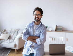 Modern Entrepreneur. Cheerful Young Eastern Man Standing Near Desk At Home Office