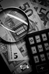 Euro bills seen through a magnifying glass and a calculator