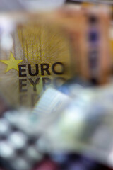 Word "Euro" on a bill seen through a magnifying glass with a defocused calculator