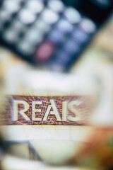 Brazilian Real bill seen through a magnifying glass with calculator background