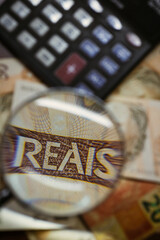 Brazilian Real bill seen through a magnifying glass with calculator background