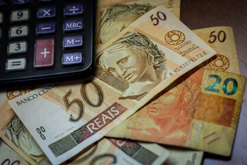 Bill of 50 Brazilian Real with a calculator and other bills under them