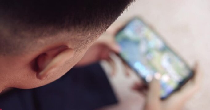 A teenage boy is addicted to online games on his smartphone.