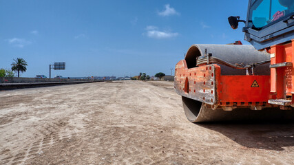 Orange road roller type ride-on with articulating-swivel on a site. Road construction in Valencia as industrial background